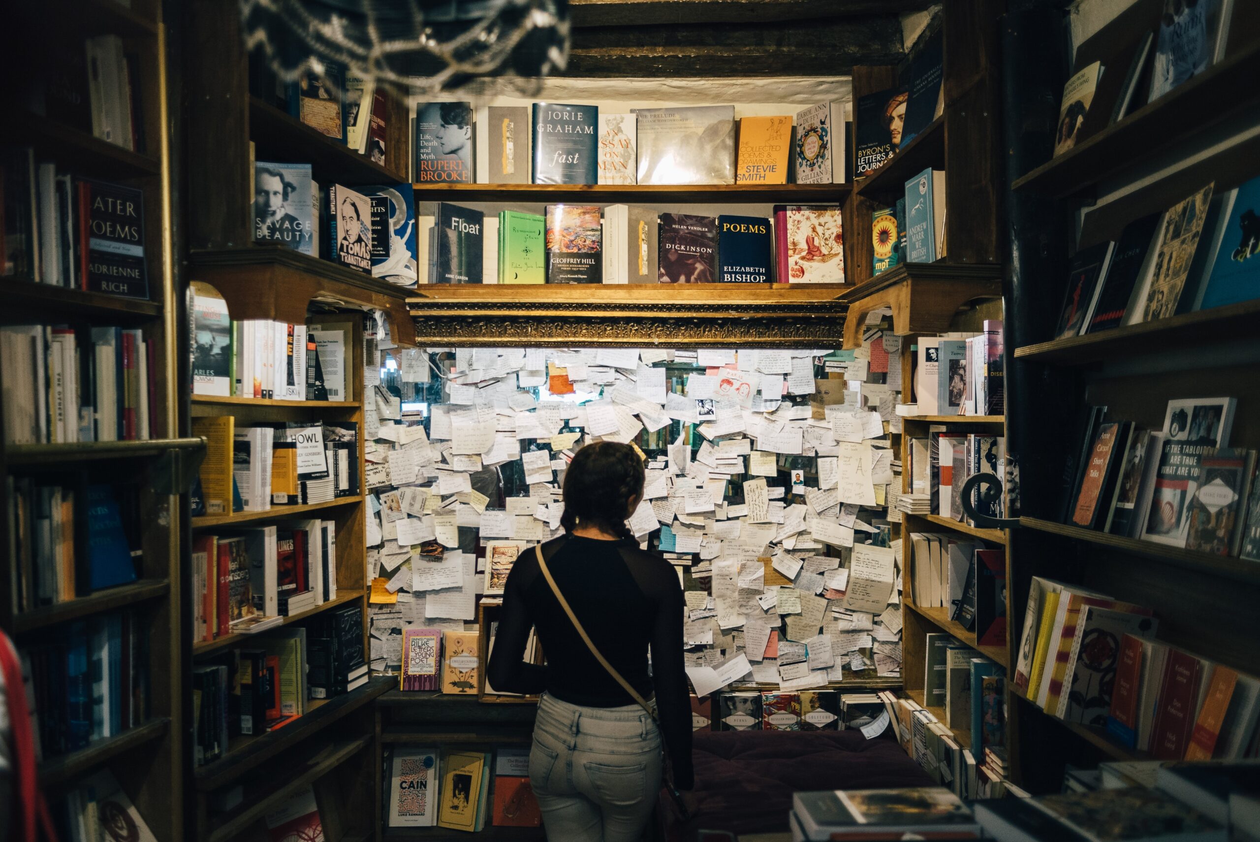 A person standing in a bookstore in front of a board covered with notes, depicting how memory shapes decision-making and innovation.